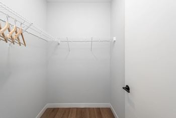 A white closet with a white wall and a hanging rack